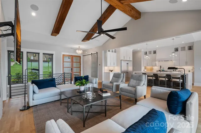 a living room with furniture kitchen view and a chandelier