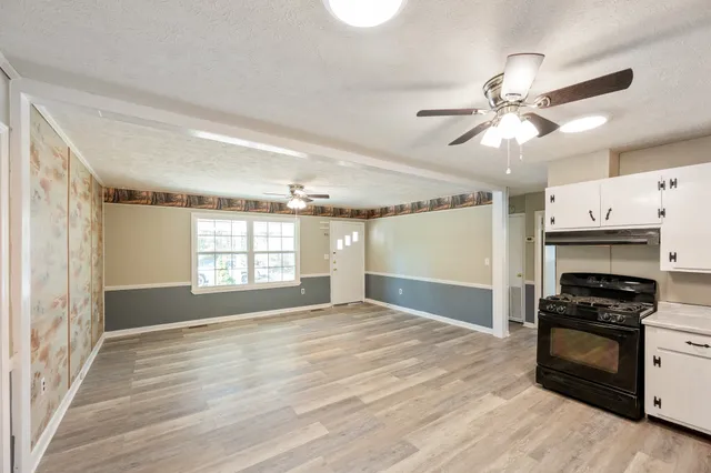 a view of an empty room with a kitchen and a window