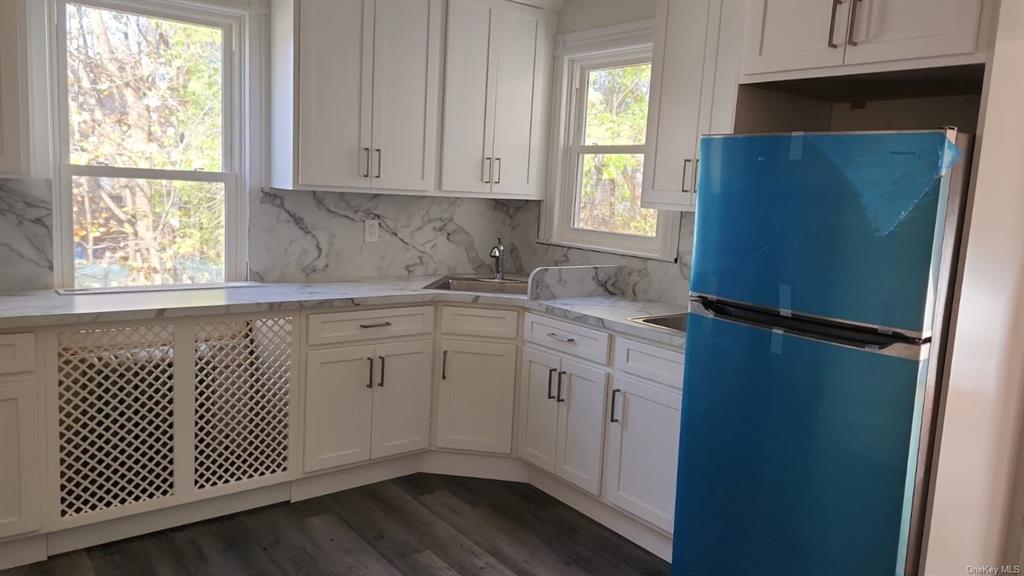 69 Saddle River Road, Unit #1 Monsey, NY 10952 - Photo 3 of 7 Kitchen with white cabinetry, backsplash, dark hardwood / wood-style flooring, and stainless steel fridge