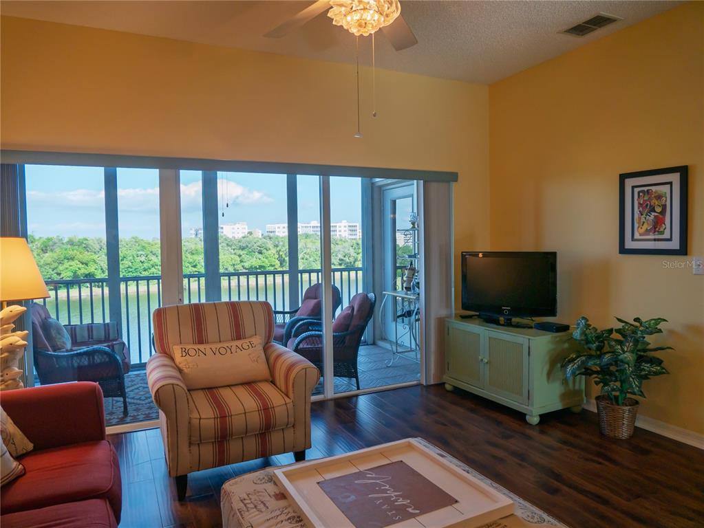 6401 99th Way North, Unit 15C St. Petersburg, FL 33708 - Photo 12 of 48 a living room with furniture a flat screen tv and a floor to ceiling window