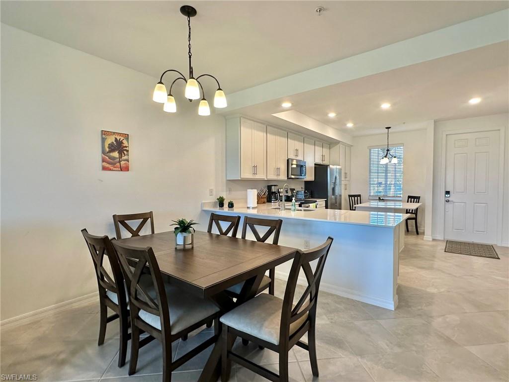 43985 Boardwalk Loop, Unit 2115 Babcock Ranch, FL 33982 - Photo 5 of 42 a dining room with wooden floor a chandelier a wooden table and chairs