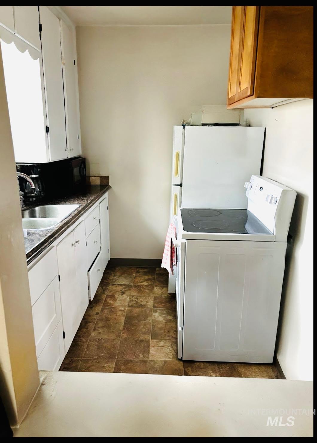 409 North 7th Street Payette, ID 83661 - Photo 2 of 23 Galley kitchen featuring white cabinetry, a stainless steel sink, and durable tile-patterned flooring