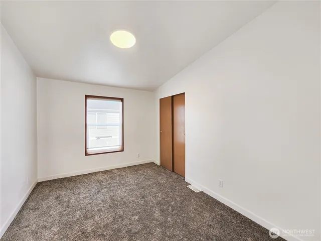 a view of an empty room with a window and closet area