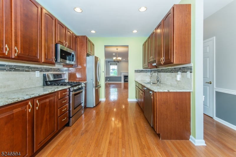 551 Coventry Drive Nutley, NJ 07110 - Photo 8 of 22 a kitchen with stainless steel appliances granite countertop wooden floors a stove and a microwave