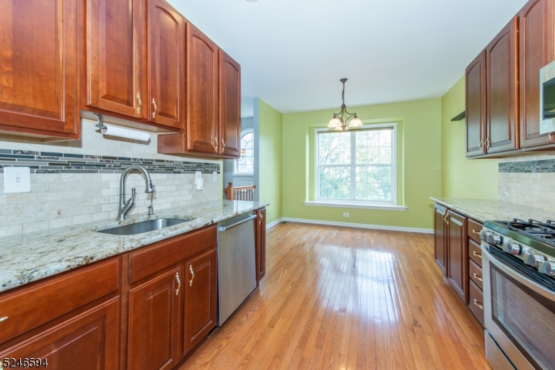 551 Coventry Drive Nutley, NJ 07110 - Photo 9 of 22 a kitchen with granite countertop wooden floors wooden cabinets a sink and a window
