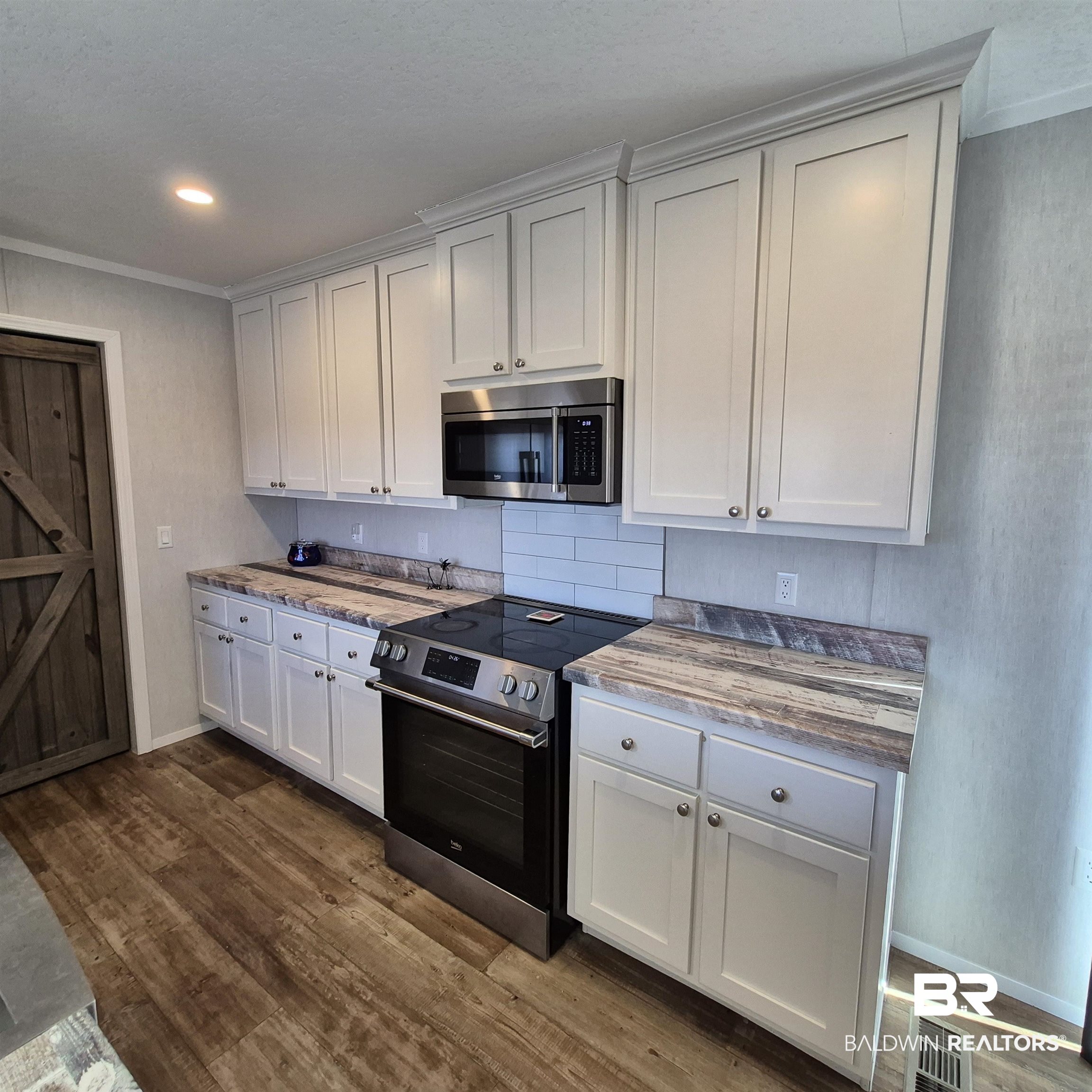8867 Old Stage Road Repton, AL 36475 - Photo 7 of 37 Kitchen featuring appliances with stainless steel finishes, dark wood-style floors, white cabinetry, ornamental molding, and recessed lighting
