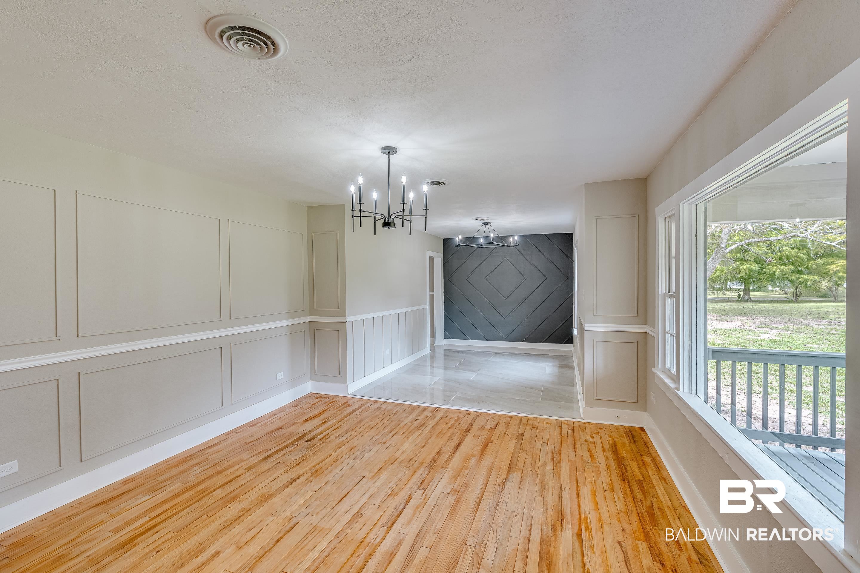 8001 16th Street Irvington, AL 36544 - Photo 4 of 35 Unfurnished dining area featuring a decorative wall, light wood-type flooring, and a chandelier