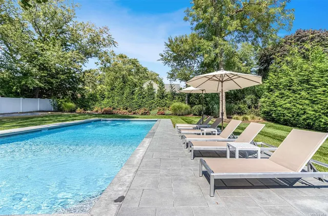 a view of backyard with swimming pool and seating space