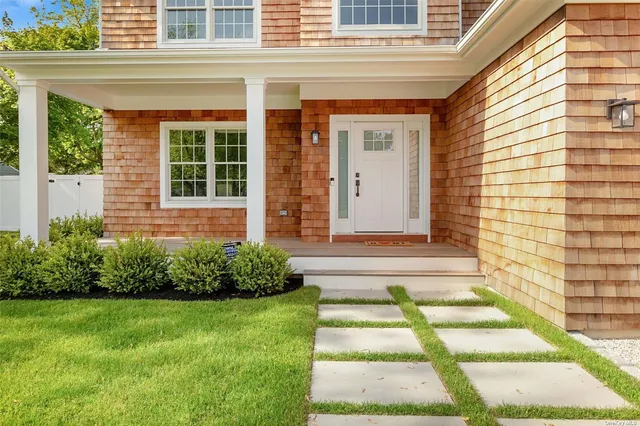 a view of brick house with a yard potted plants and a table and chair