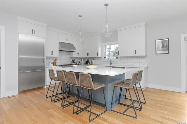a kitchen with stainless steel appliances kitchen island granite countertop a dining table chairs and a refrigerator