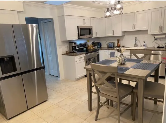 a kitchen with stainless steel appliances granite countertop a refrigerator a stove a sink a microwave and a dining table