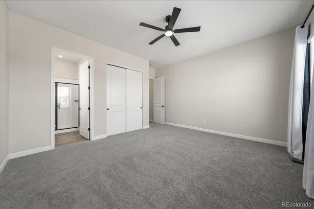 an empty room with ceiling fan and window