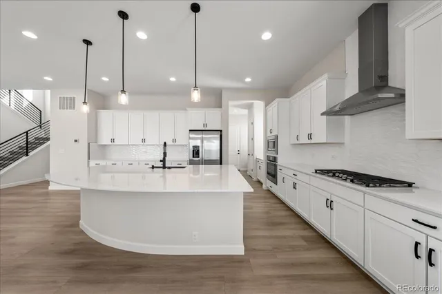 a large white kitchen with lots of counter space a sink appliances and cabinets