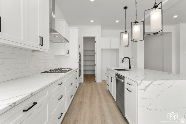 707 Spring Lily Drive St. George, UT 84790 - Photo 15 of 43 White shaker cabinetry with black hardware, stone countertops, stainless steel appliances, wood-finish flooring, and a walk-in pantry
