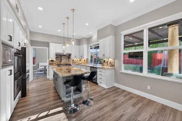 a dining hall with stainless steel appliances kitchen island granite countertop a dining table chairs and granite counter tops