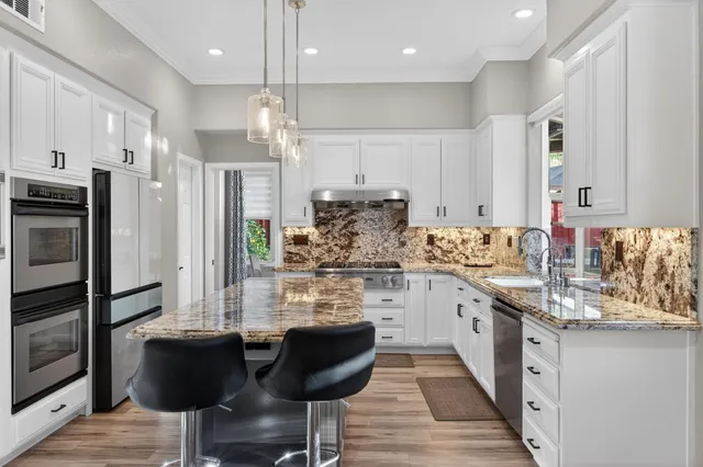 a kitchen with stainless steel appliances kitchen island granite countertop a sink refrigerator and cabinets
