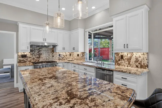 a kitchen with stainless steel appliances kitchen island granite countertop a stove sink and cabinets