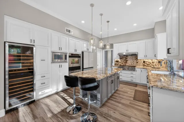 a kitchen with kitchen island granite countertop a sink cabinets and stainless steel appliances
