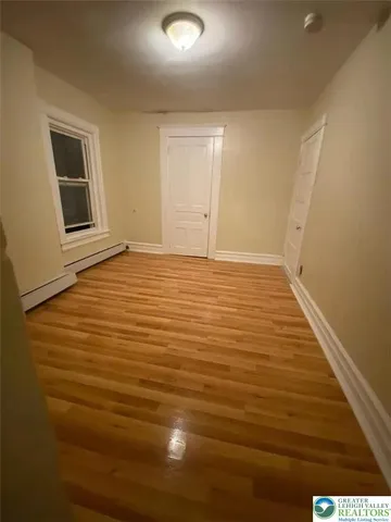 a view of an empty room with wooden floor and a window