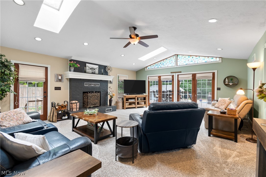 443 Merriman Road Akron, OH 44303 - Photo 11 of 44 Vaulted ceiling living space featuring a dark-toned brick fireplace with a white mantel, multiple skylights, recessed lighting, and a ceiling fan