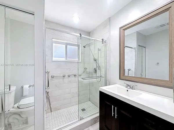 a bathroom with a double vanity sink toilet mirror and shower