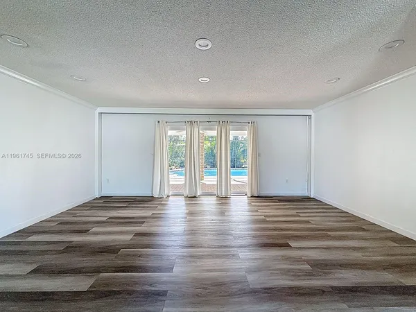 a view of an empty room with window and wooden floor