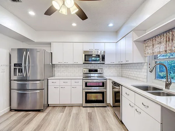 a kitchen with stainless steel appliances a refrigerator sink and microwave