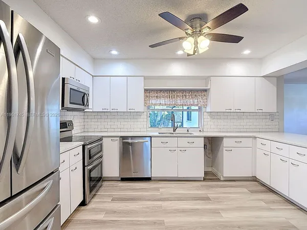 a kitchen with granite countertop a sink stainless steel appliances and cabinets