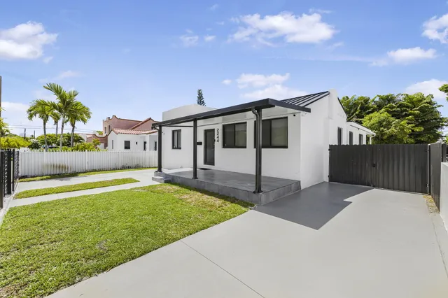 a front view of a house with a yard and palm tree