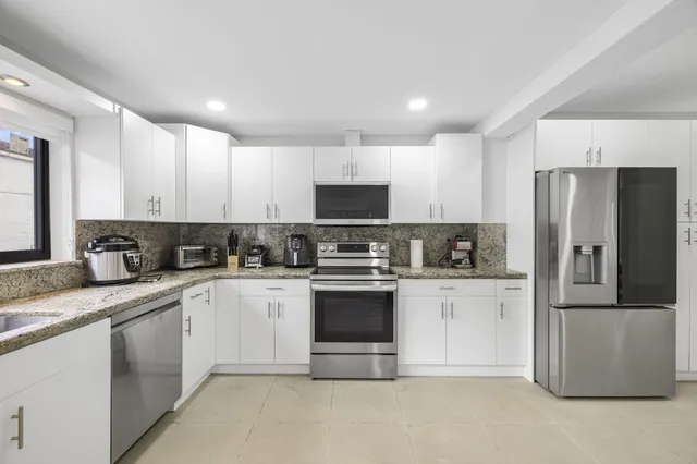 a kitchen with granite countertop white cabinets and stainless steel appliances