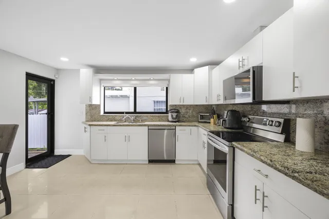 a kitchen with granite countertop white cabinets and stainless steel appliances