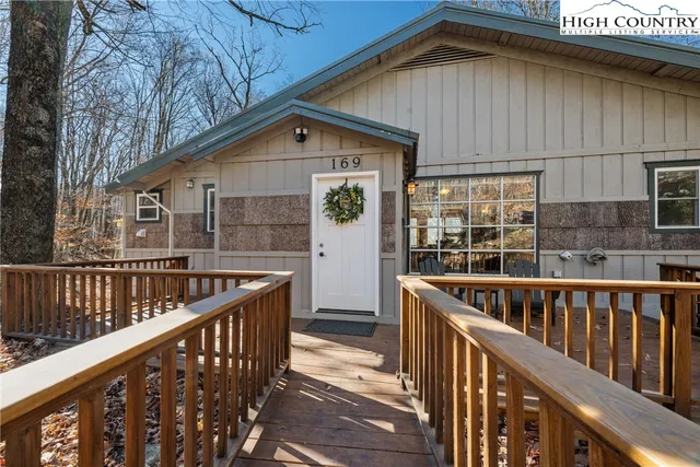 a view of house with wooden deck and furniture