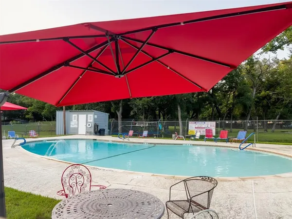a view of swimming pool with lawn chairs under an umbrella