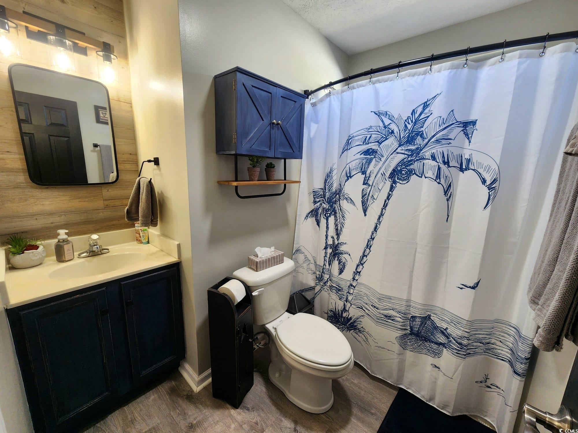 9883 Conifer Lane Murrells Inlet, SC 29576 - Photo 12 of 24 Full bathroom featuring wood walls, toilet, vanity
