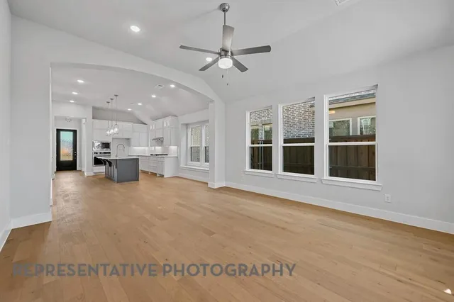 a view of an empty room with kitchen and window