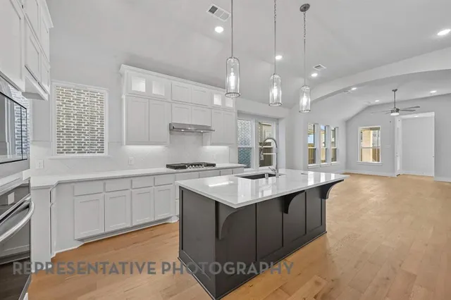 a kitchen with a stove a sink a center island and windows