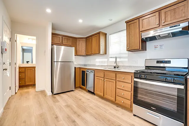 a kitchen with stainless steel appliances granite countertop a refrigerator stove top oven and sink