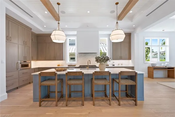 a large kitchen with lots of counter space a sink appliances and living room view