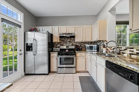 a kitchen with stainless steel appliances granite countertop a stove a sink and a refrigerator