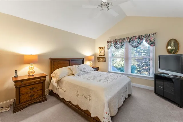 a spacious bedroom with a bed and a flat tv screen on dresser