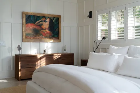 a bedroom with a bed and painting on the wall