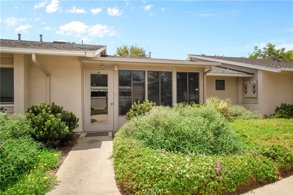a view of a house with potted plants and a table and chair