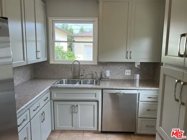 a kitchen with stainless steel appliances granite countertop a sink a stove and a refrigerator with wooden cabinets