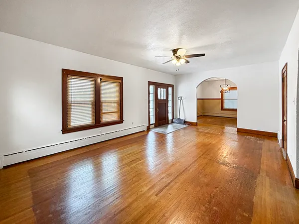 a view of empty room with wooden floor and fan