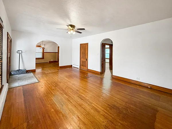 a view of empty room with wooden floor and fan