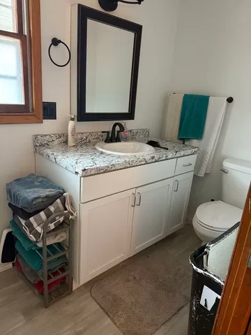 a bathroom with a granite countertop toilet sink and mirror