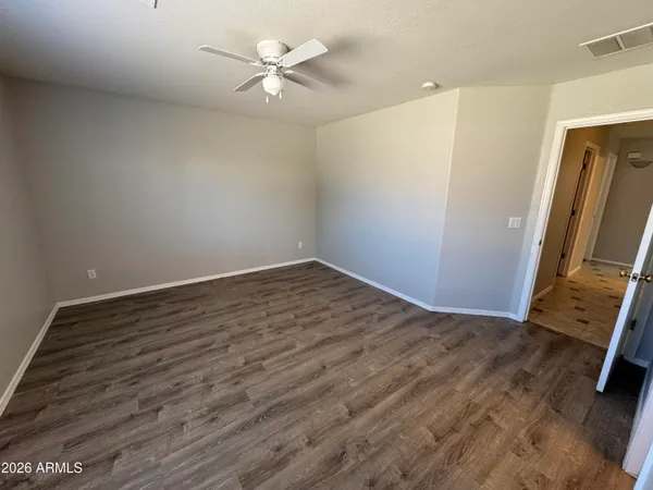 an empty room with wooden floor and fan