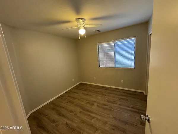 an empty room with a chandelier fan and windows