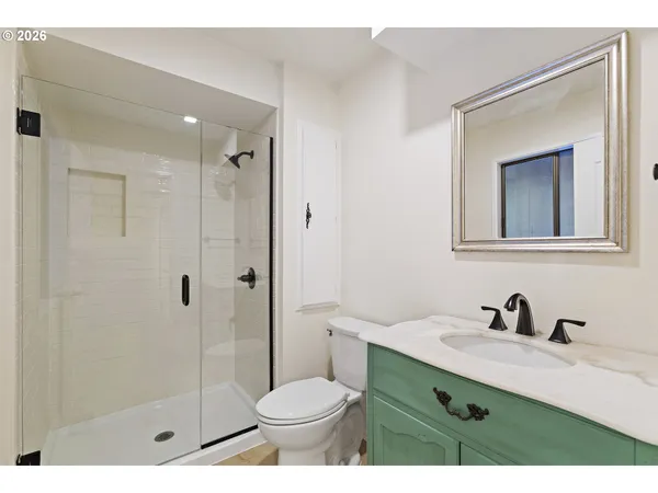 a bathroom with a shower sink vanity mirror and toilet