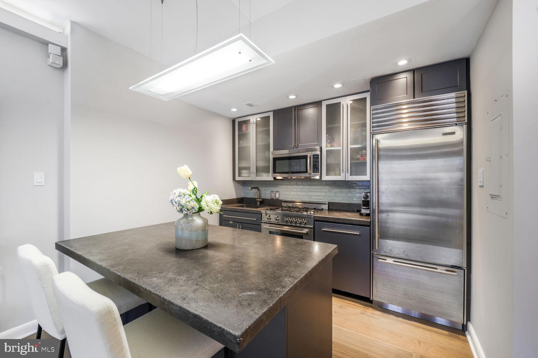 3251 Prospect Street Northwest, Unit 410 Washington, DC 20007 - Photo 5 of 16 a kitchen with stainless steel appliances kitchen island granite countertop a refrigerator a stove white cabinets and chairs